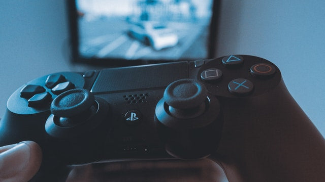 Gamer holding a PS4 controller in front of a screen